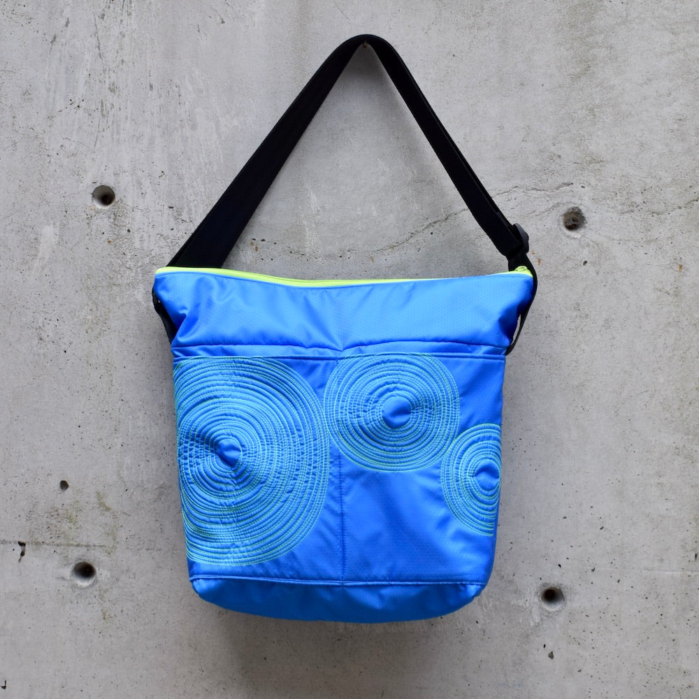 large zippered bag with outer pockets, cross body bag. adjustable strap, two interior pockets,  two exterior pockets, YKK zipper, made in canada, made in toronto, handmade, one of a kind, topstitching, spirals, perfect for travel, perfect everyday, work, gym, play, travel, durable, lightweight, machine washable, electric blue with lime stitching