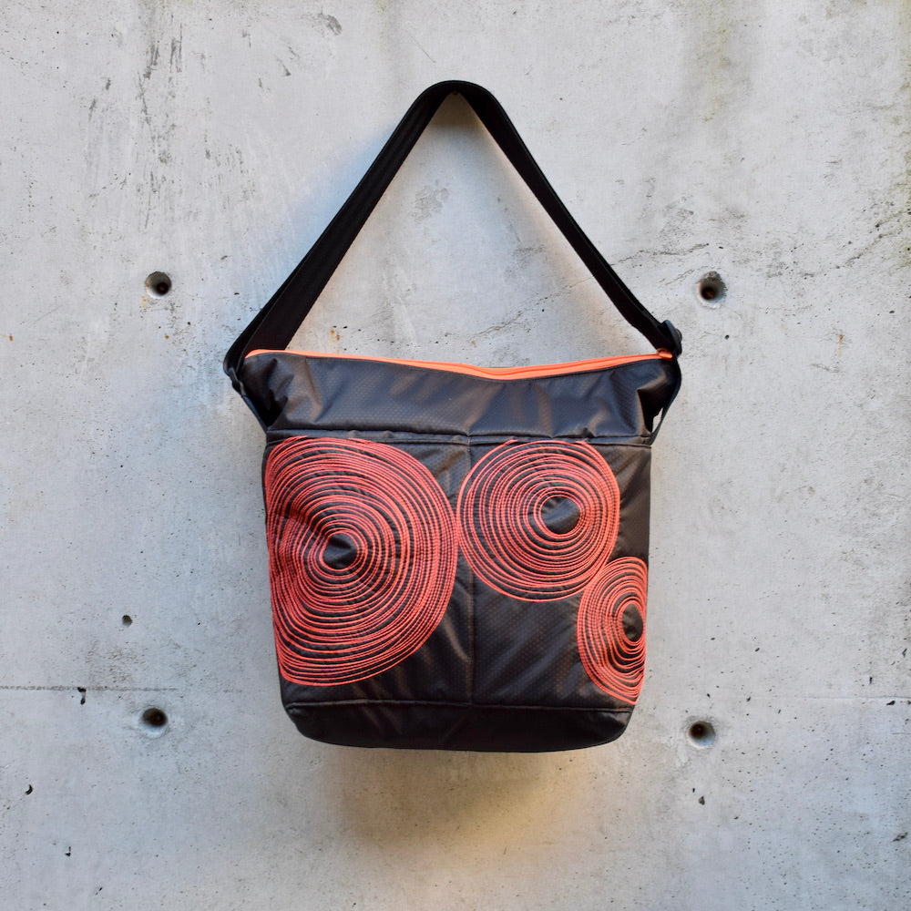 large zippered bag with outer pockets, cross body bag. adjustable strap, two interior pockets,  two exterior pockets, YKK zipper, made in canada, made in toronto, handmade, one of a kind, topstitching, spirals, perfect for travel, perfect everyday, work, gym, play, travel, durable, lightweight, machine washable, chocolate brown with orange stitching