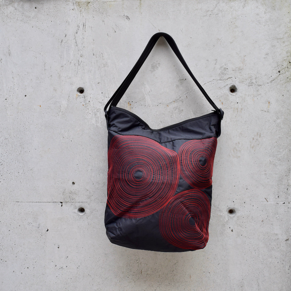 dinner bag, cross body bag. adjustable strap, 2 interior pockets, YKK zipper, made in canada, made in toronto, handmade one of a kind, topstitching, spirals, perfect for travel, perfect everyday, work, gym, play, travel, black with red stitching, durable, lightweight and machine washable,